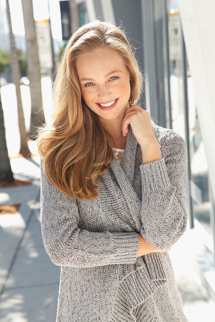 A young blonde woman wearing a grey cardigan