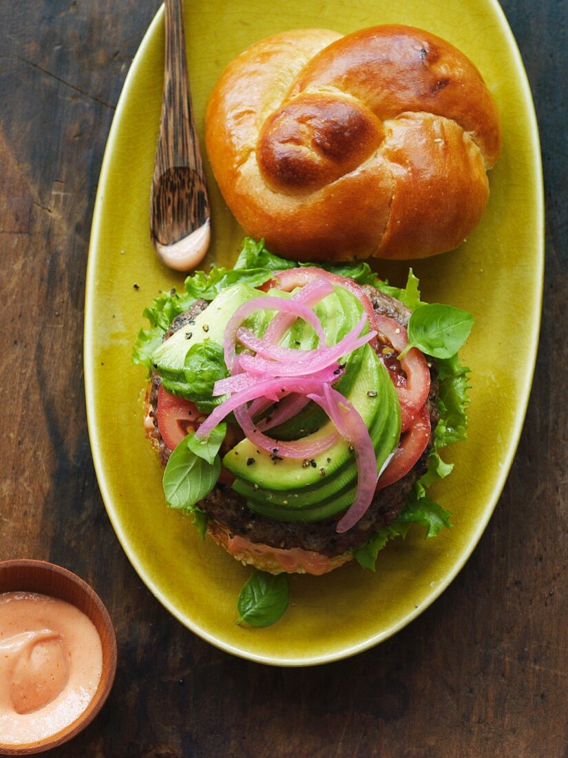 Hamburger im Brioche Brötchen mit Avocado und Zwiebel auf Teller