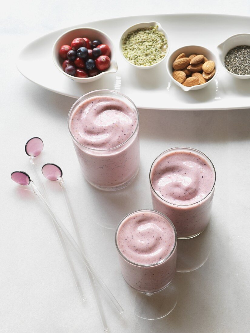 Drei Smoothies mit Zutaten: Chiasamen, Hanfsamen, Cranberries, Heidelbeeren und Mandeln