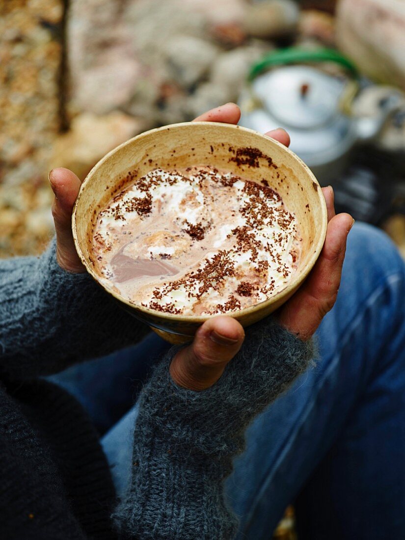 Hands holding a bowl of bicerin (chocolate and coffee drink, Turin)