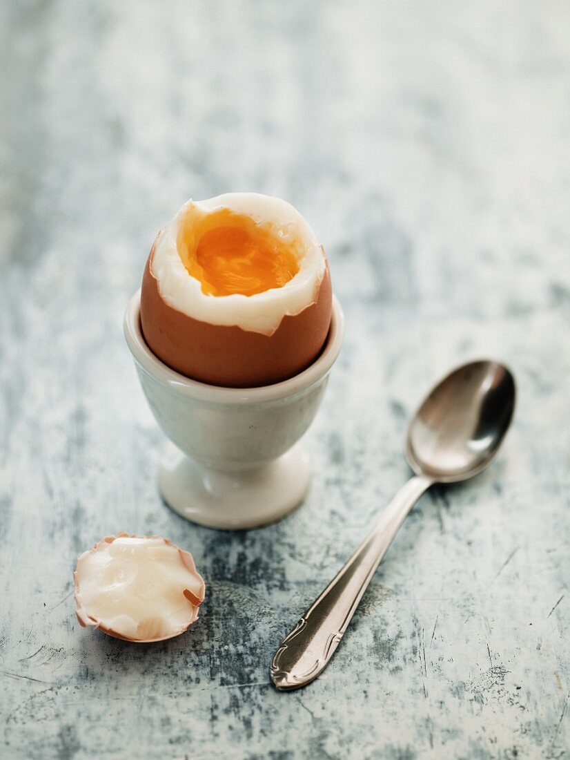 Soft Boiled Egg in an Egg Cup with Topped Cracked Off and Yolk Running Over