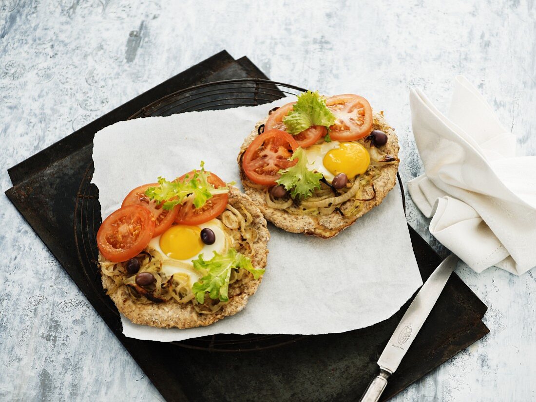 Rye bread pizzas with fried eggs, tomatoes, olives and onions