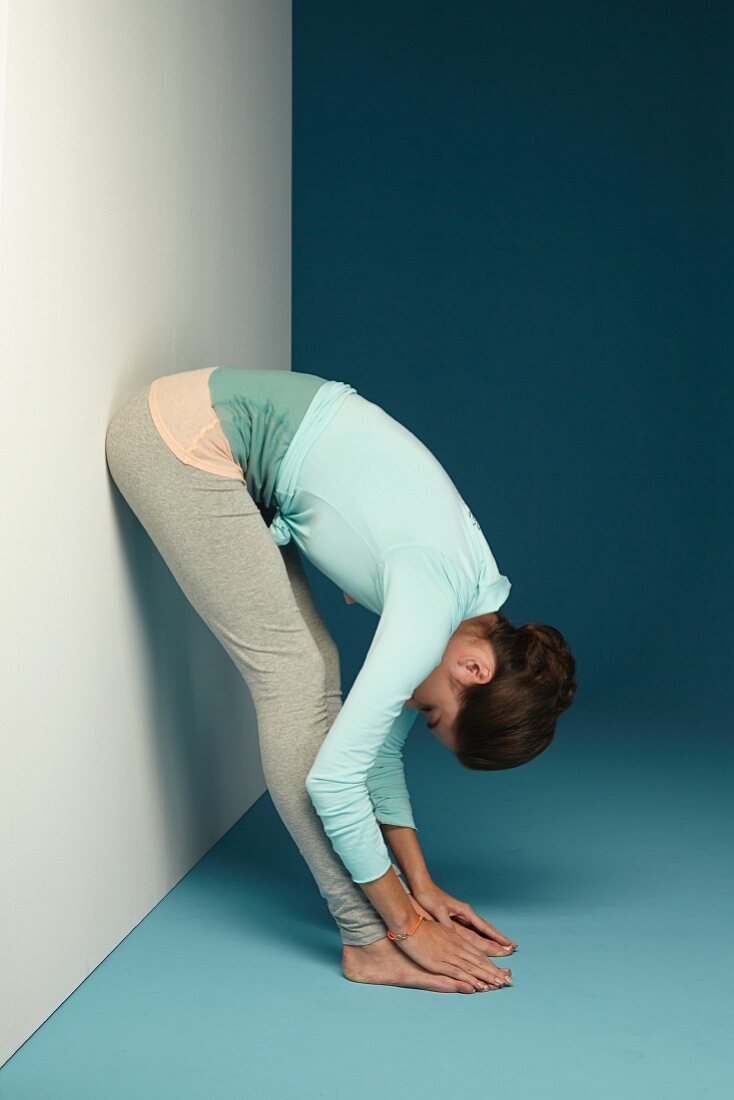 Forward bend from standing against a wall