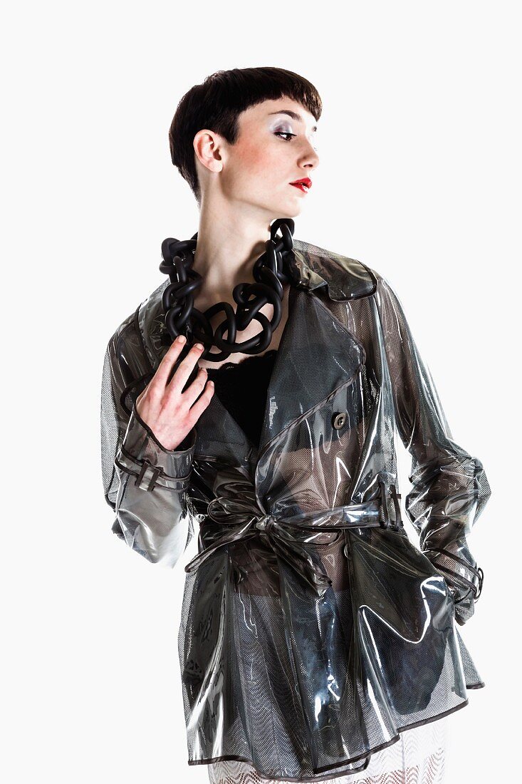 Junge Frau mit Garcon-Schnitt in schwarzem transparentem Regenmantel mit Modeschmuck
