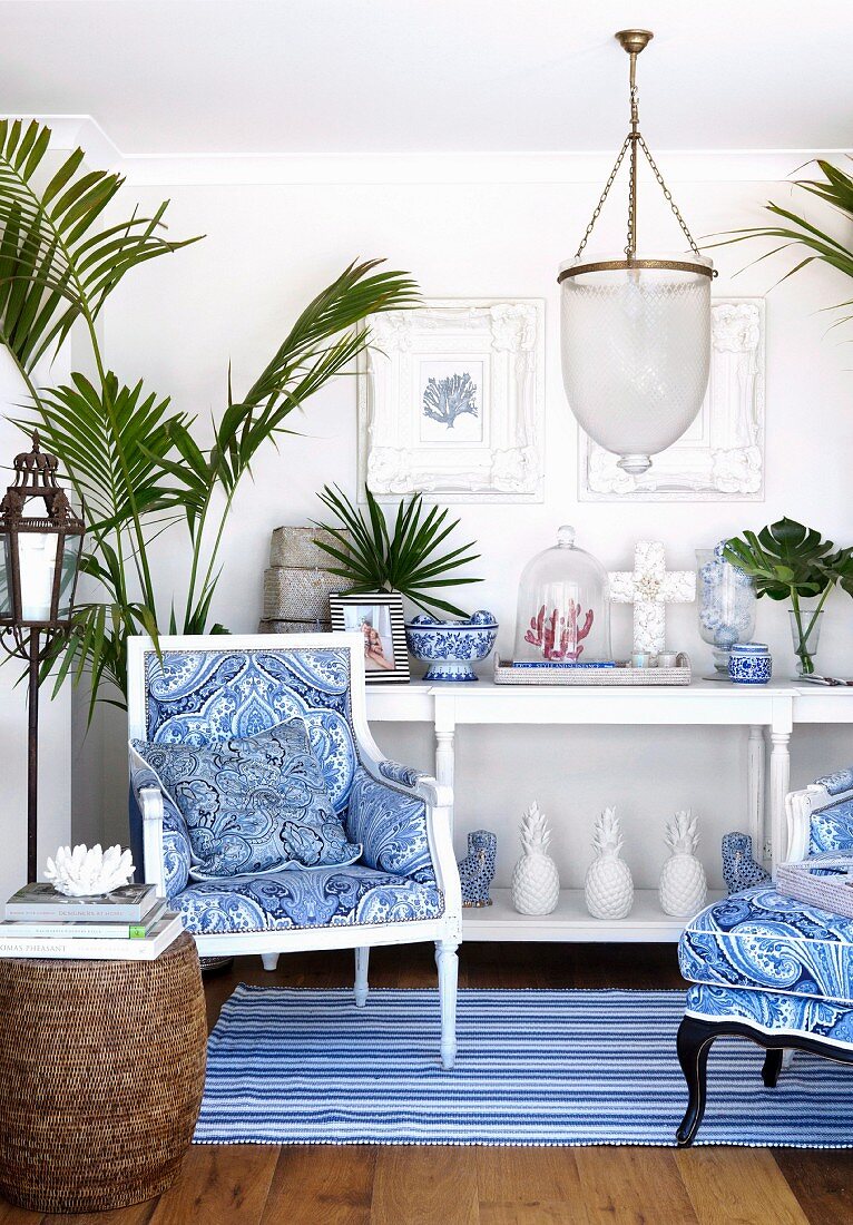 Armchairs with blue and white covers on striped rug in front of white console table in maritime ambiance