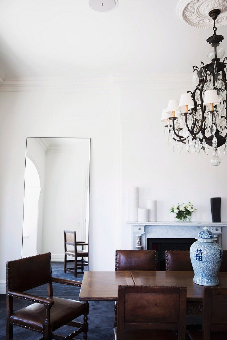 Dining area with wooden table, antique leather chairs, fireplace and chandelier