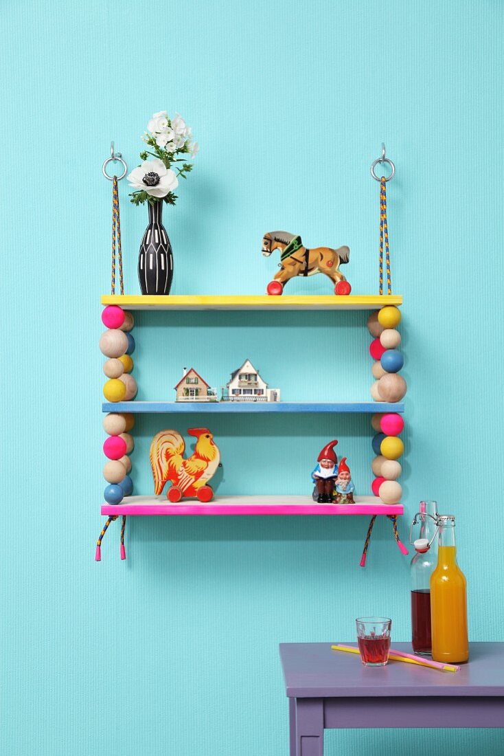 Colourful, hand-made shelves with wooden beads threaded on climbing ropes and decorated with vintage-style toys