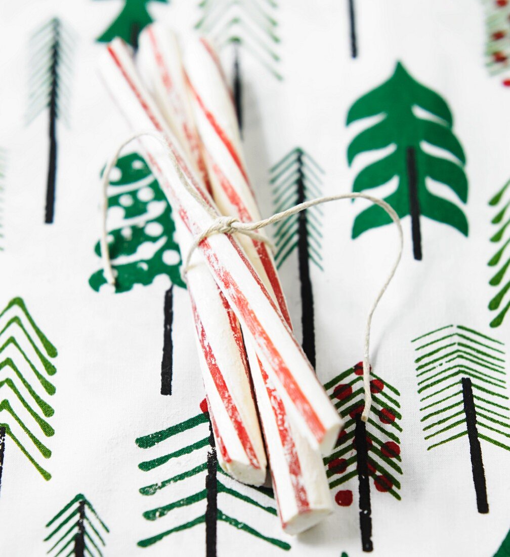 Sticks of peppermint rock on a table with a cloth decorated with Christmas trees