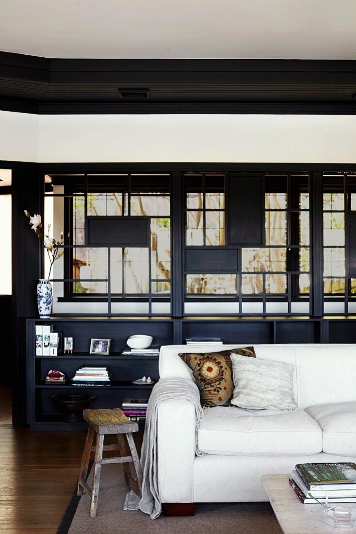 White sofa in front of dark shelves below Japanese-style lattice structure