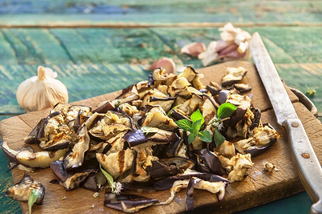 Chopped grilled aubergine and peppermint on a rustic wooden board