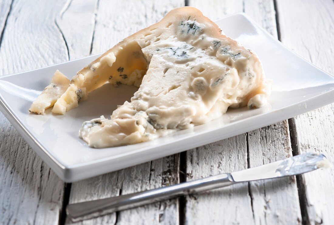 A wedge of Gorgonzola cheese on a white plate