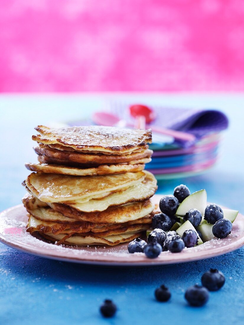 A stack of pancakes with blueberries and pear