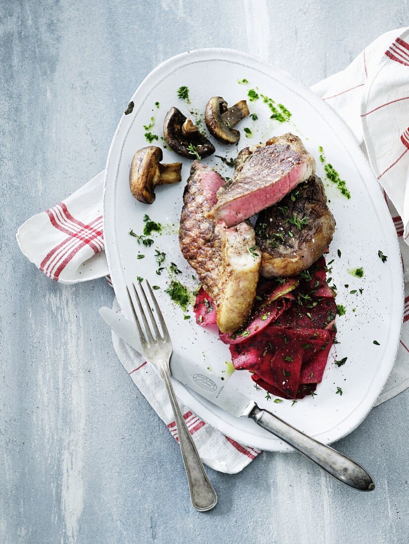 Rare grilled steaks with beetroot, mushrooms and herbal oil