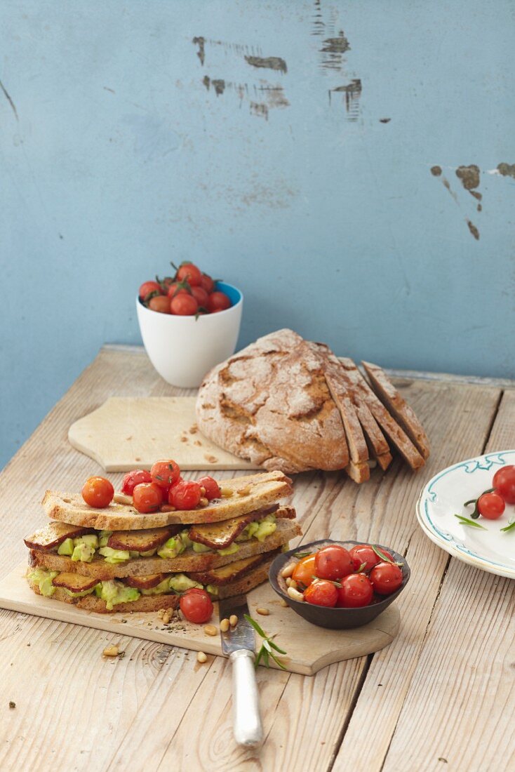 A double-decker sandwich with tofu, avocado and tomatoes