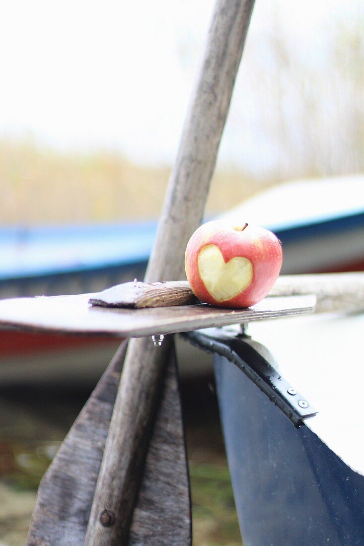 An apple with a heart carved into it on a boat