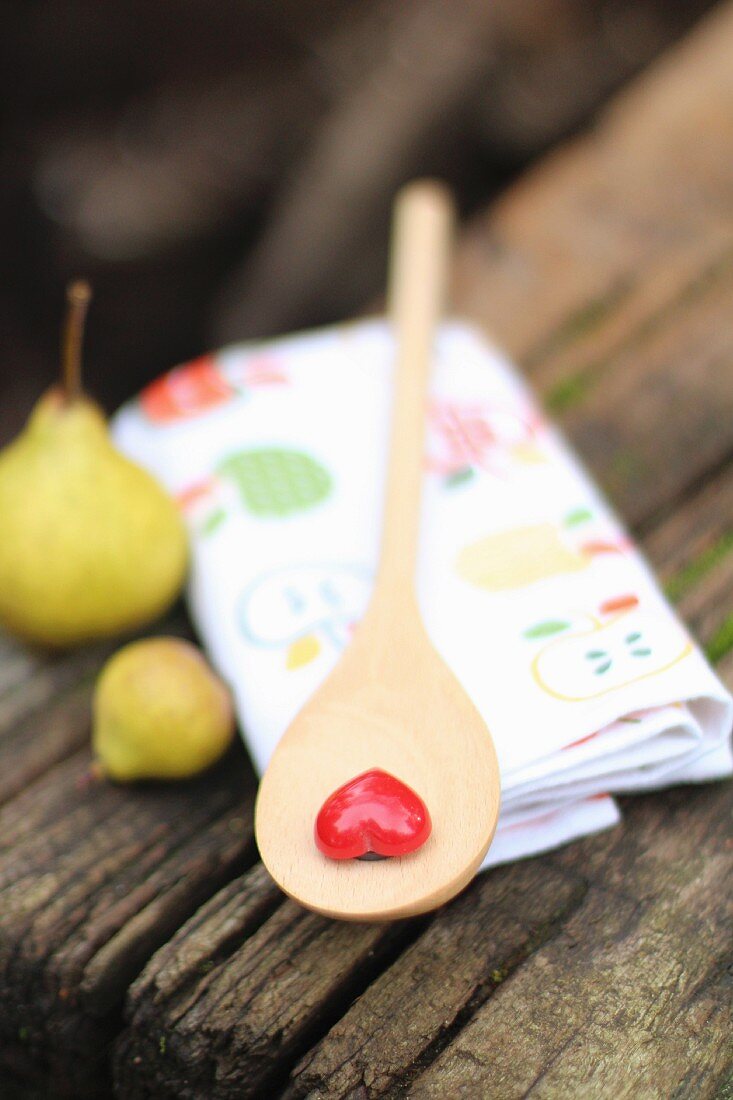 A wooden spoon with a heart and two small pears