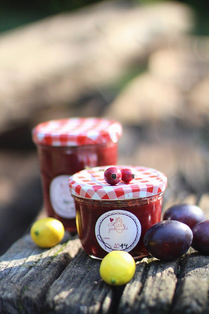 Jars of plum jam on a wooden board