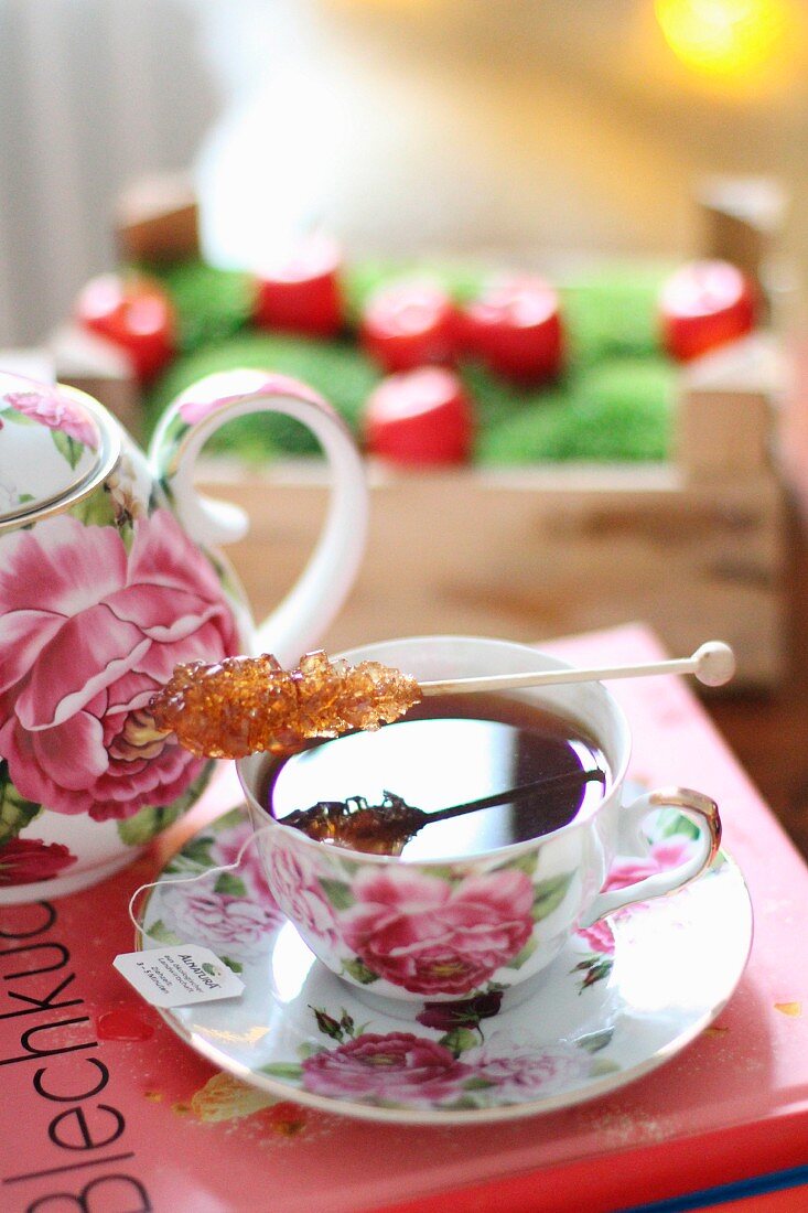 A rock candy stick on a rose patterned tea cup