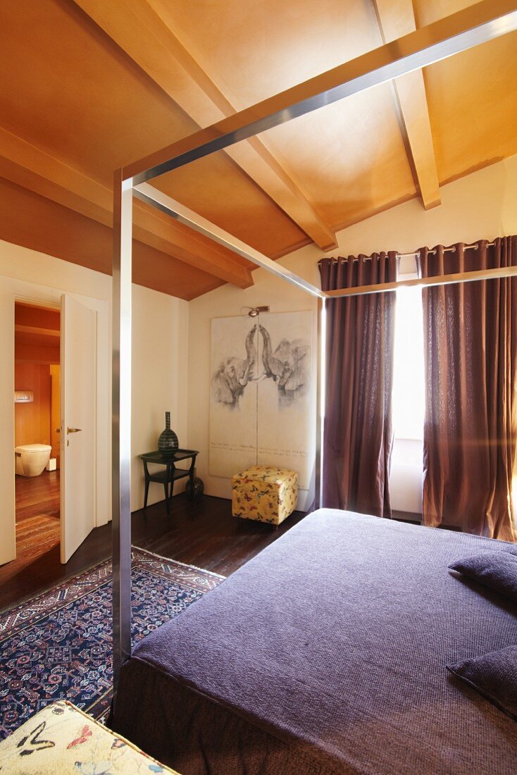 Bett mit violetter Husse und minimalistischem modernem Metallgestell in traditionellem elegantem Ambiente, Blick in Bad-Ensuite durch offene Tür