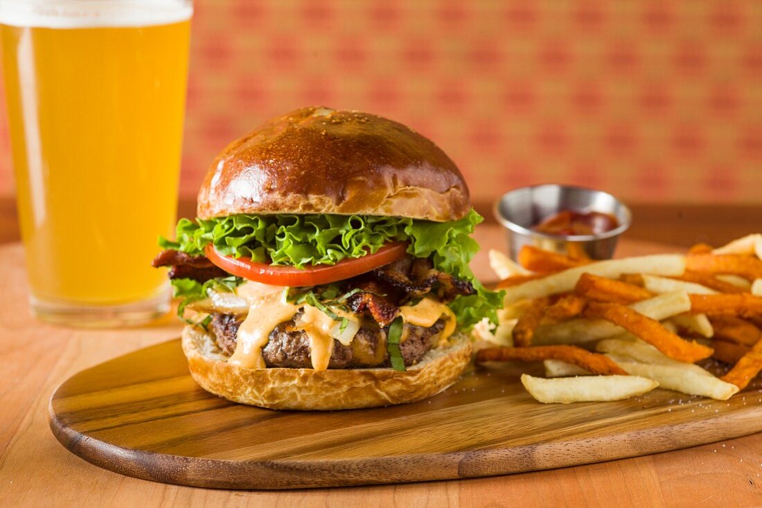 Hamburger mit Aioli auf Schneidebrett mit Pommes frites