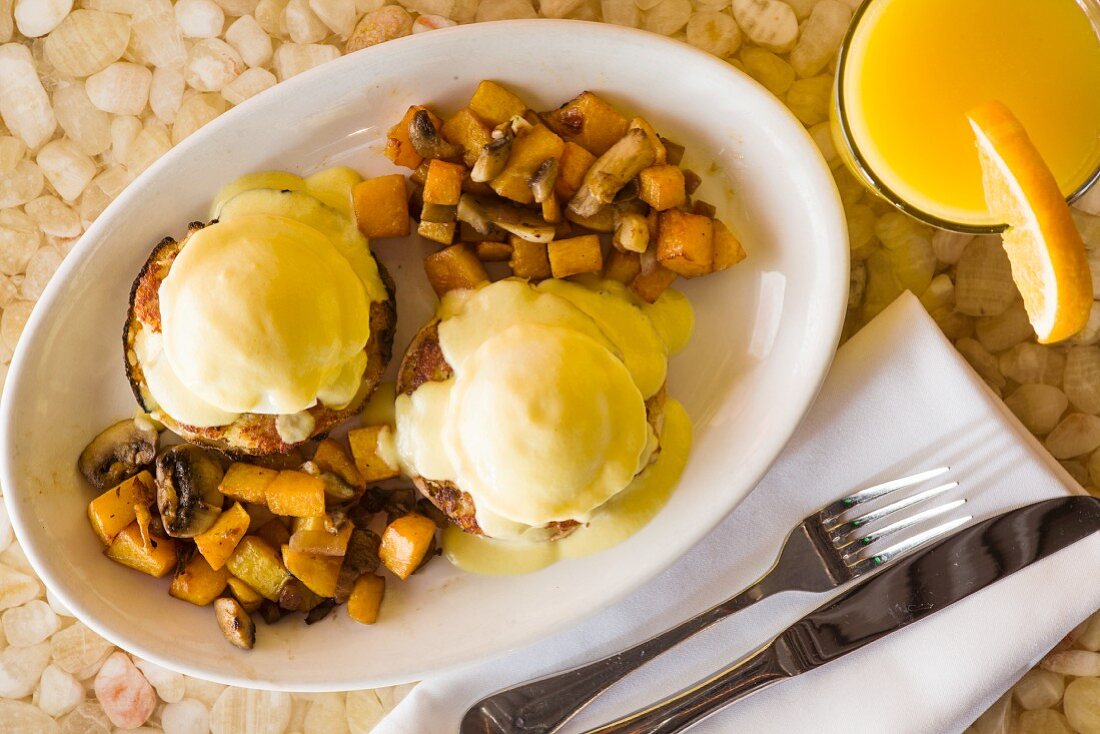 Eggs Benedict with fried potatoes and mushrooms