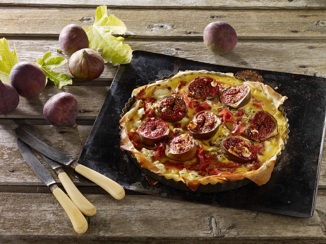 A puff pastry fig, smoked ham and feta cheese quiche on a baking tray