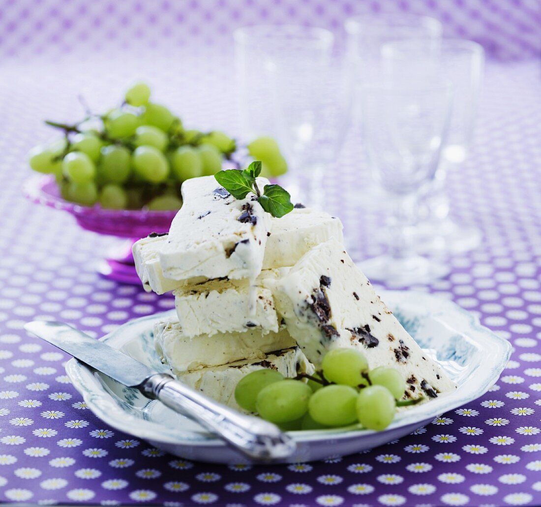 Slices of vanilla parfait with dark chocolate served with green grapes