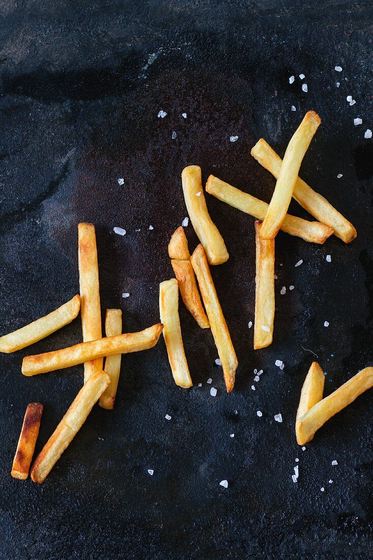 Pommes frites mit Meersalz auf schwarzer Metalloberfläche