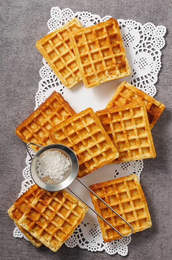 Waffeln und Zuckersieb auf Tortenpapier