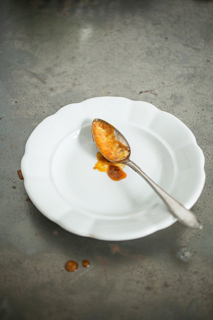 A spoon with sauce on a plate