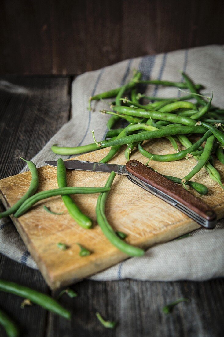 Green beans on a chopping board with a folding knife