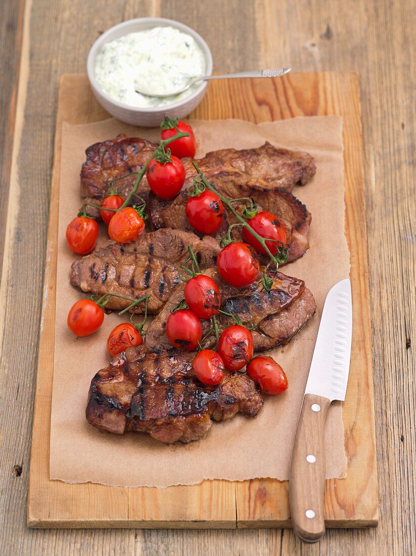 Grilled pork collar with cherry tomatoes and tzatziki