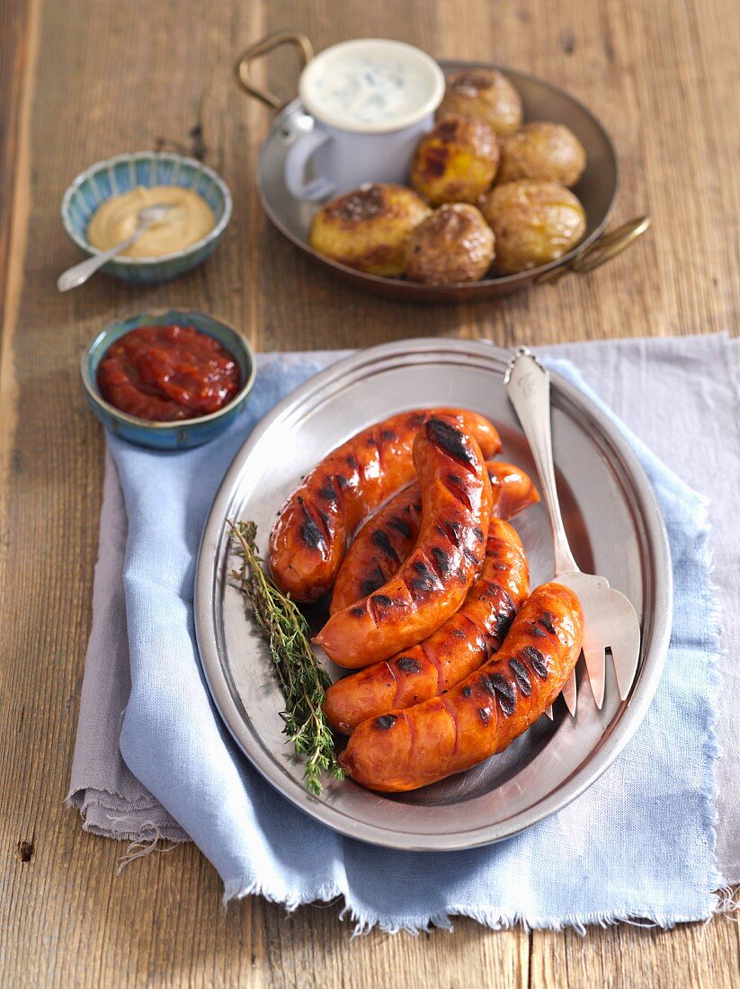 Grilled sausage with baked potatoes and sauces