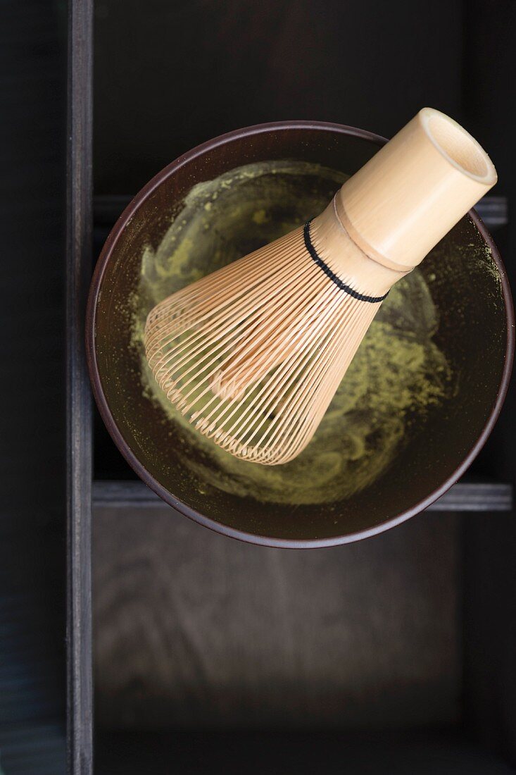 A matcha tea whisk in a matcha tea bowl with matcha tea powder