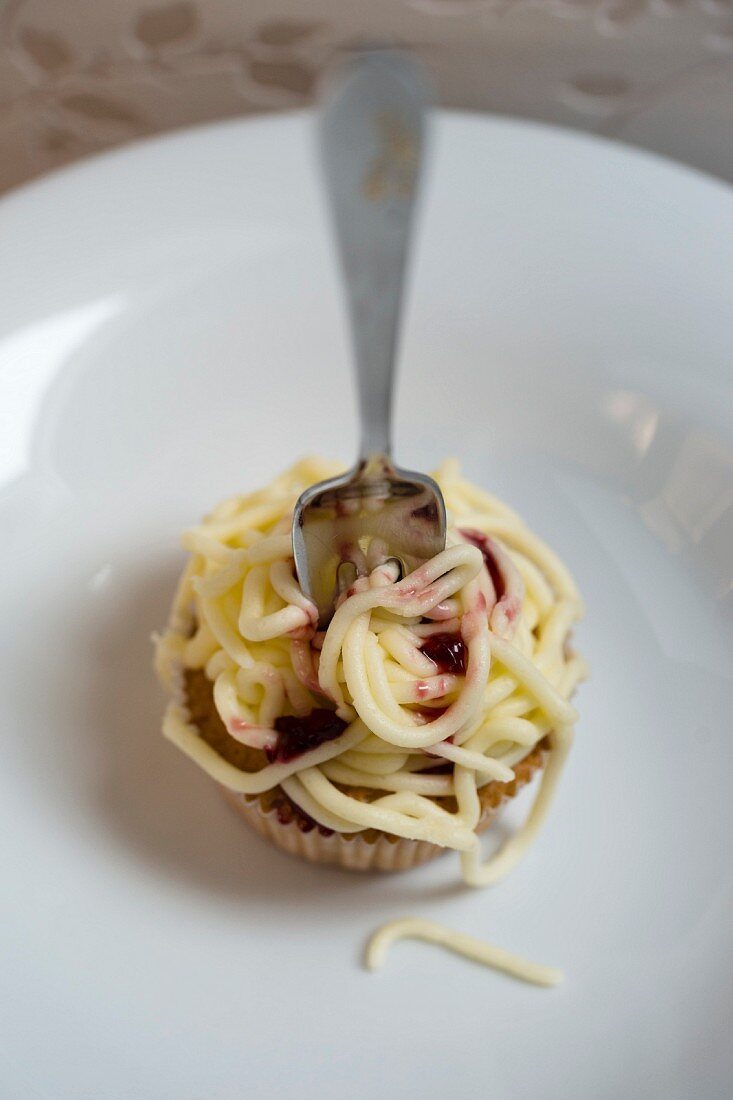 A cupcake decorated with buttercream spaghetti and sauce
