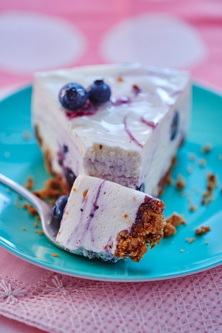 Slice of Cheesecake with Blueberry Topping on Stack of White Plates, Forks