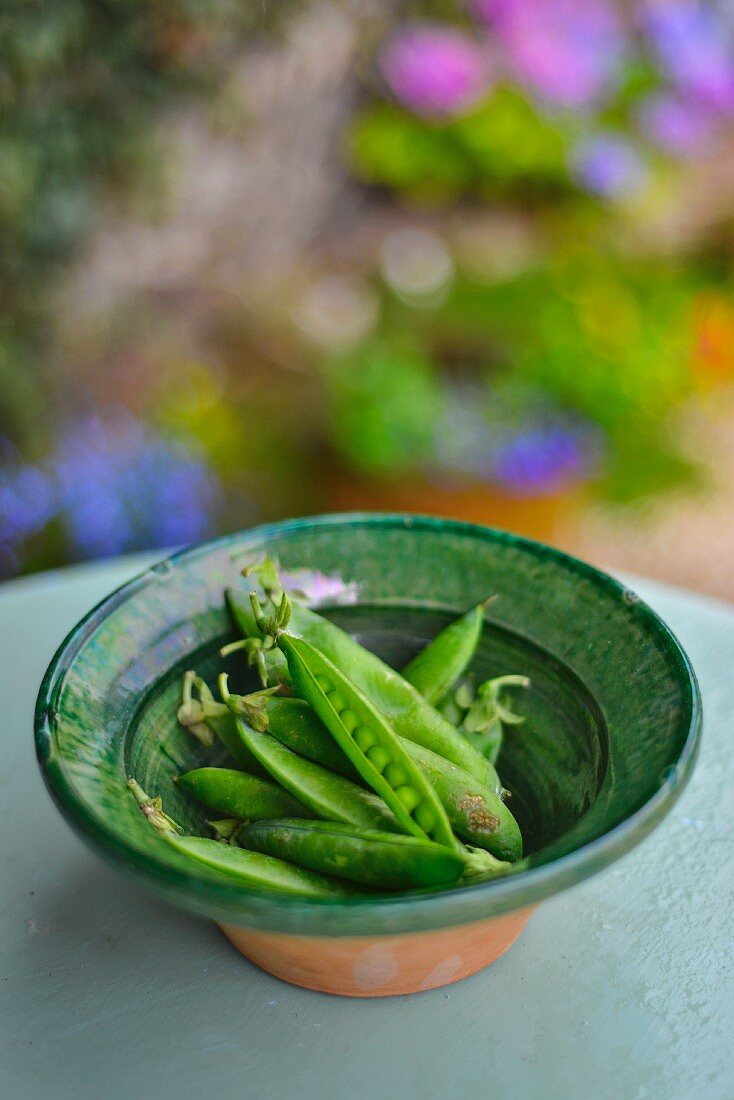 Fresh pea pods in a green bowl
