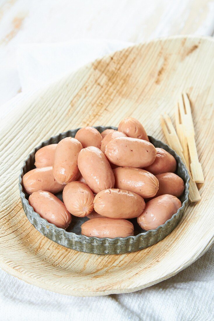 Cooked mini sausages in a bowl with wooden forks