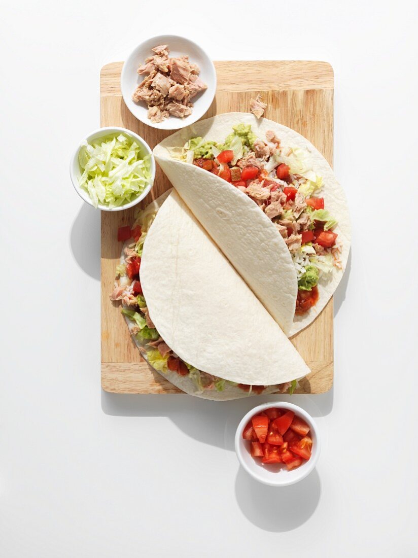 A burrito with tuna, tomatoes and salad