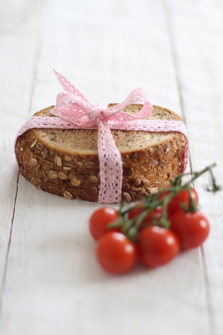 Slices of bread ties with a lace ribbon next to cherry tomatoes