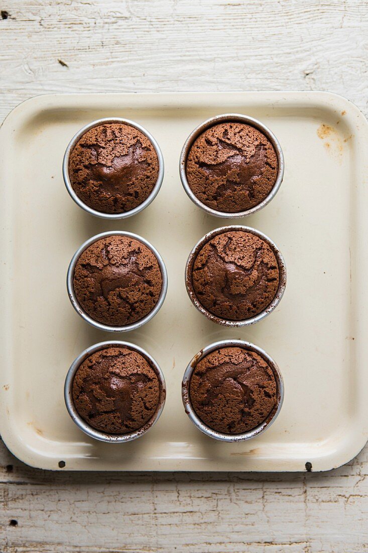 Warm fondants au chocolat in baking tins on a baking tray