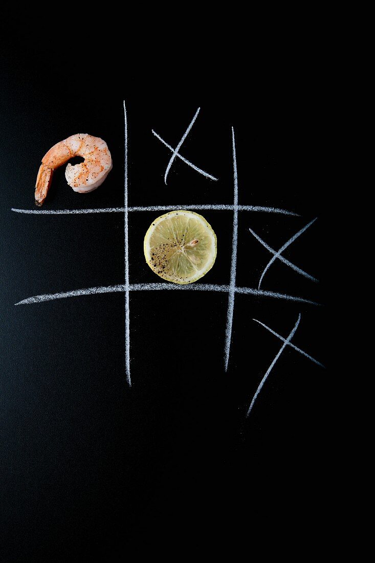 A prawn and a lemon slice on a chalkboard