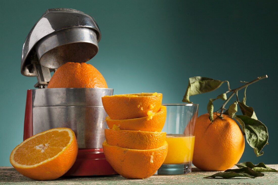 Stillleben mit frischem Orangensaft, Orangenpresse und ausgepressten Orangen