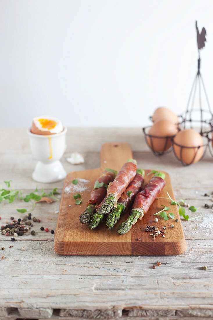 Green asparagus wrapped in ham with a soft boiled egg
