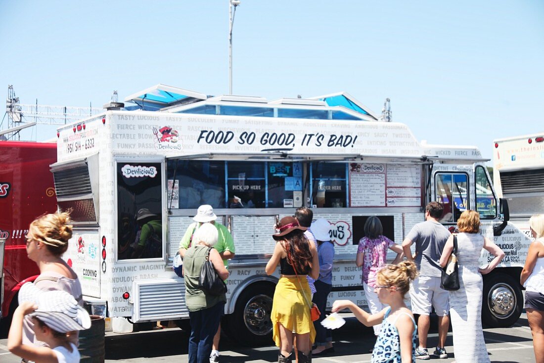 Customers buying fast food from a food truck festival in California, USA