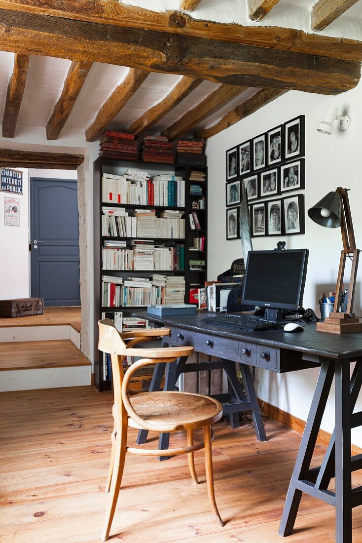 Thonet armchair at black desk in rustic interior with wooden ceiling