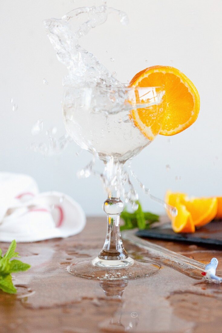 Wasserglas mit Splash und Orangenscheibe