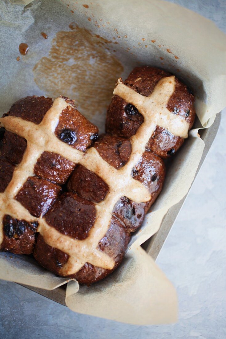 Hot cross buns in a baking tin lined with parchment paper