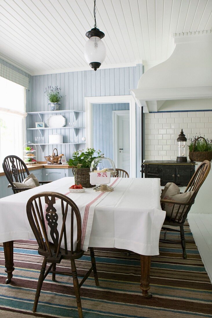 Erdbeerpflanze auf Esstisch und Windsor-Stühle in Wohnküche mit Holzverkleidung