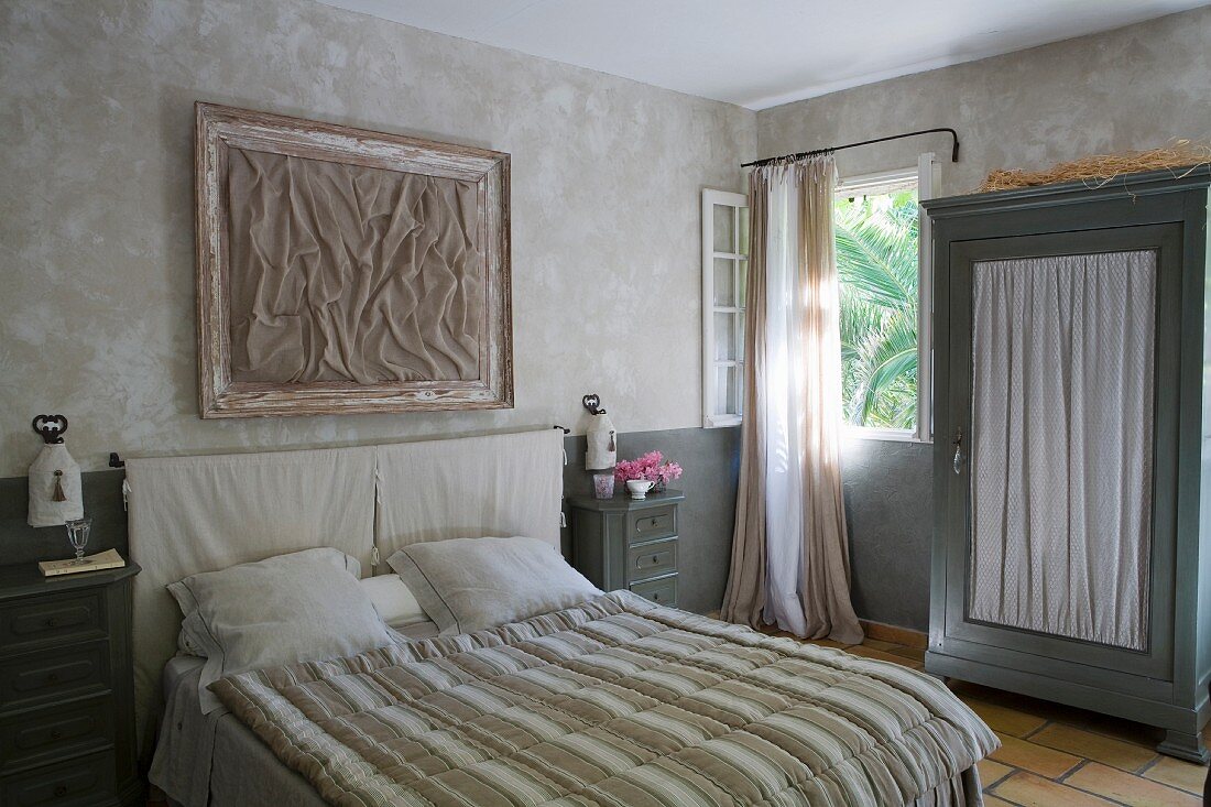 Doppelbett mit gestreiftem Überwurf, Schrank mit Türfüllung aus gerafftem Stoff im Schlafzimmer in Naturtönen